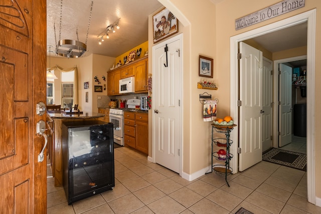 kitchen featuring light tile patterned floors, white appliances, and beverage cooler