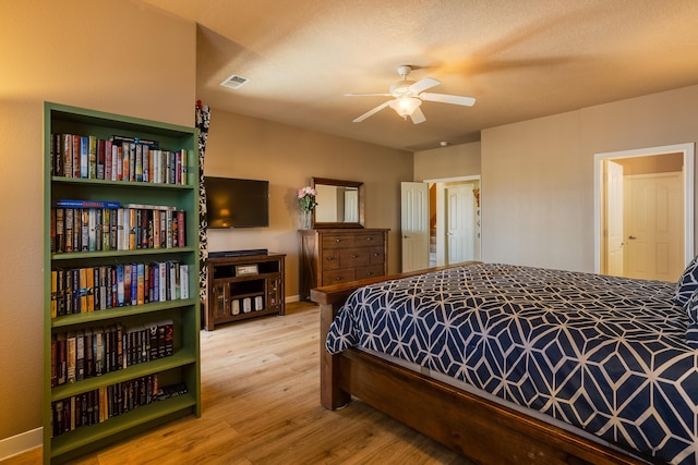 bedroom with a textured ceiling, wood-type flooring, and ceiling fan