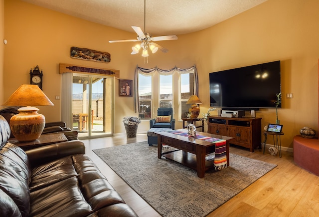 living room featuring vaulted ceiling, ceiling fan, light hardwood / wood-style floors, and a textured ceiling