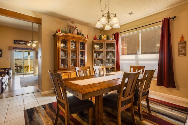 dining area featuring ceiling fan with notable chandelier, light tile patterned floors, and a textured ceiling