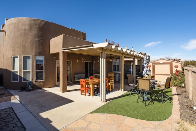 rear view of property with a storage shed, ceiling fan, and a patio area