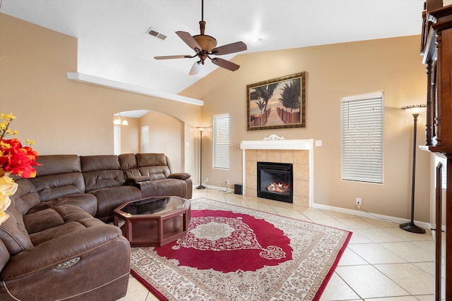 tiled living room with a fireplace, ceiling fan, and vaulted ceiling