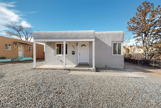 southwest-style home with fence, a porch, and stucco siding