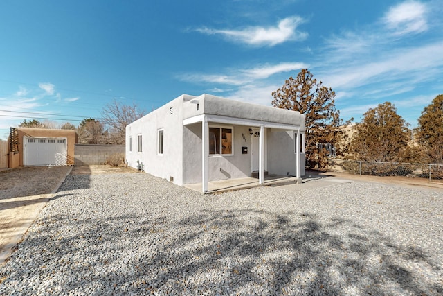 view of front of property featuring an outdoor structure, fence, and stucco siding