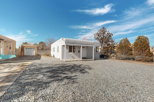 view of front facade with fence, driveway, and stucco siding