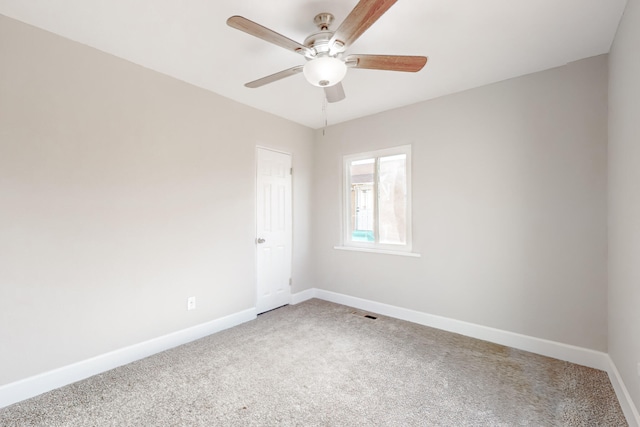 carpeted spare room featuring a ceiling fan and baseboards