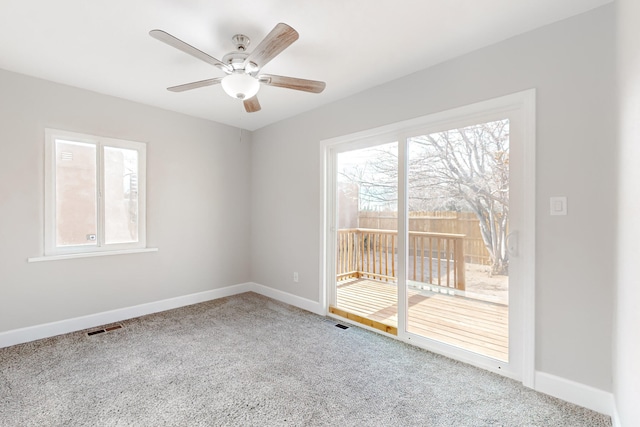 carpeted spare room with ceiling fan, visible vents, and baseboards