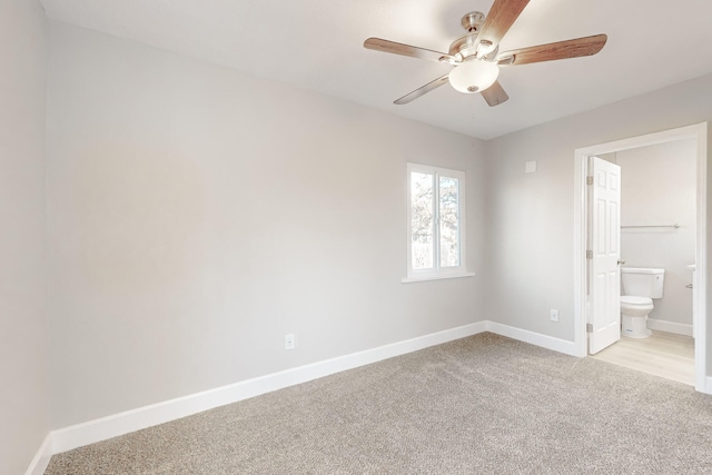 unfurnished bedroom with light carpet, a ceiling fan, baseboards, and connected bathroom