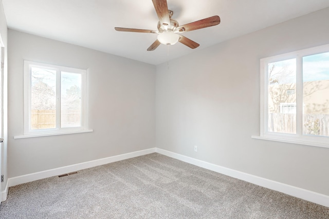 spare room with ceiling fan, carpet floors, visible vents, and baseboards