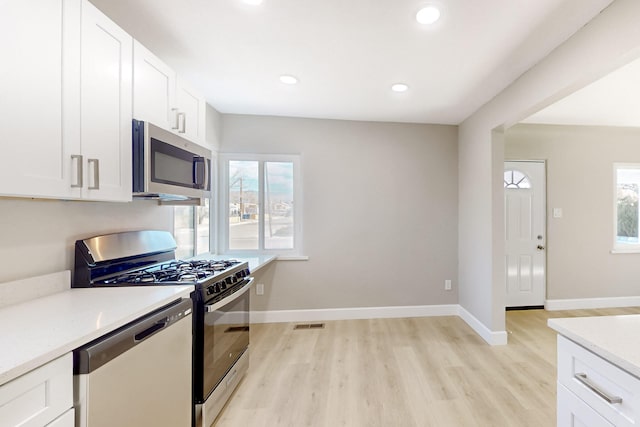 kitchen featuring stainless steel appliances, a wealth of natural light, light countertops, and white cabinets