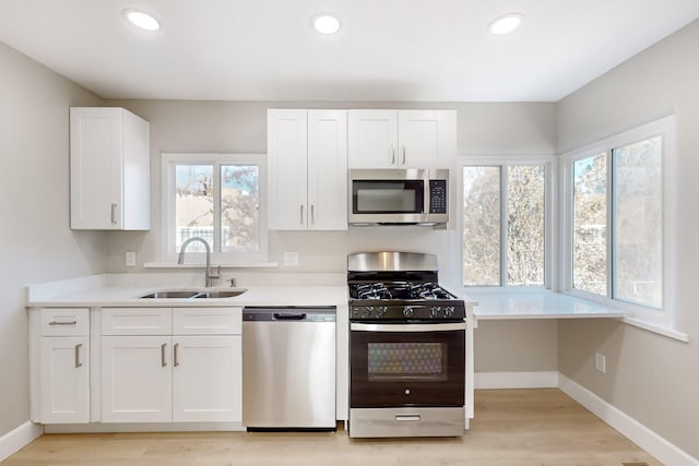 kitchen featuring stainless steel appliances, light countertops, white cabinets, and a sink