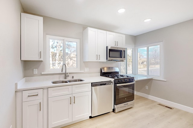 kitchen featuring a sink, white cabinetry, visible vents, baseboards, and appliances with stainless steel finishes