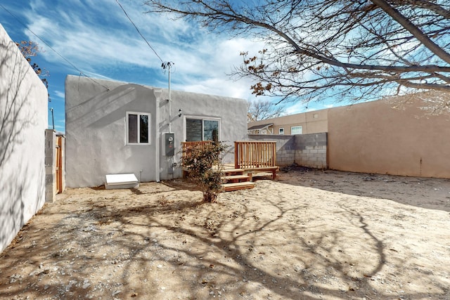 back of house featuring fence, a wooden deck, and stucco siding