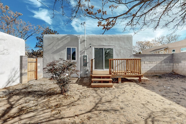 back of property with a wooden deck, fence, and stucco siding