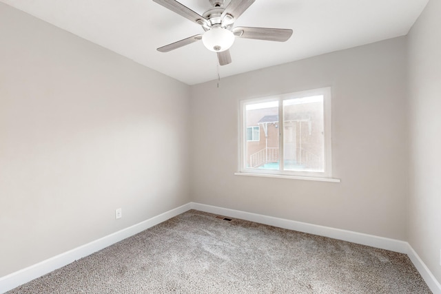 spare room with light carpet, a ceiling fan, visible vents, and baseboards