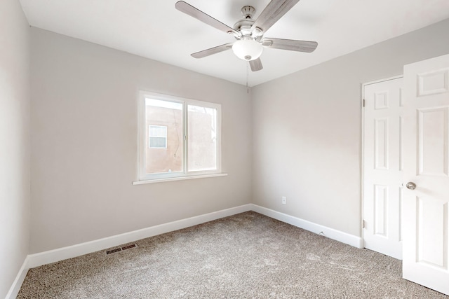 carpeted spare room with baseboards, visible vents, and a ceiling fan