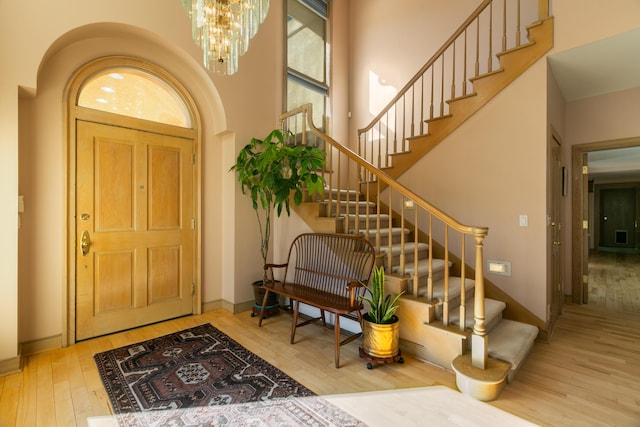 entryway featuring hardwood / wood-style flooring, a towering ceiling, and an inviting chandelier