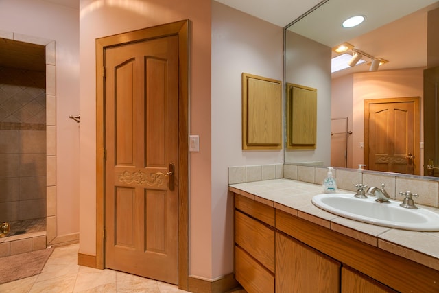 bathroom featuring a tile shower, vanity, and tile patterned floors