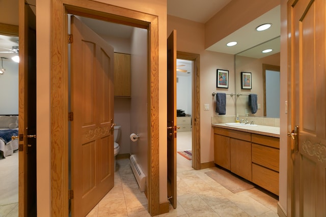 bathroom featuring ceiling fan, vanity, toilet, and a baseboard heating unit