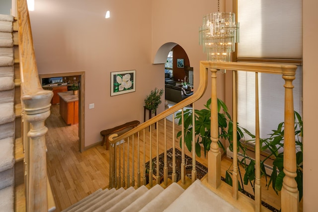 stairway with a notable chandelier and hardwood / wood-style flooring