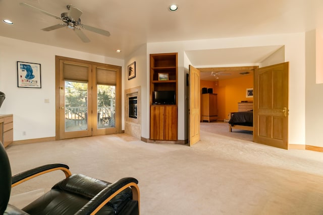 living room featuring light colored carpet, ceiling fan, and built in shelves