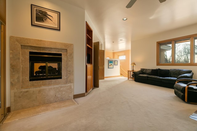 carpeted living room featuring ceiling fan, a tiled fireplace, and a wealth of natural light