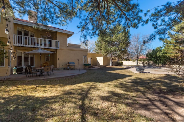 exterior space featuring a balcony, a patio area, and a lawn