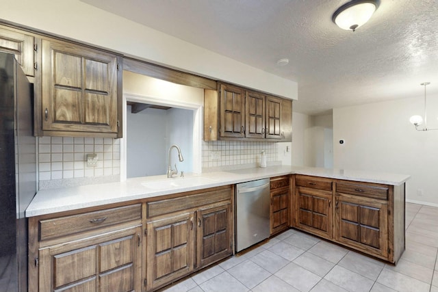 kitchen featuring pendant lighting, sink, stainless steel appliances, decorative backsplash, and kitchen peninsula