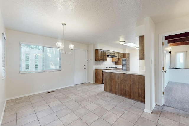 kitchen with a healthy amount of sunlight, decorative light fixtures, light tile patterned floors, and backsplash