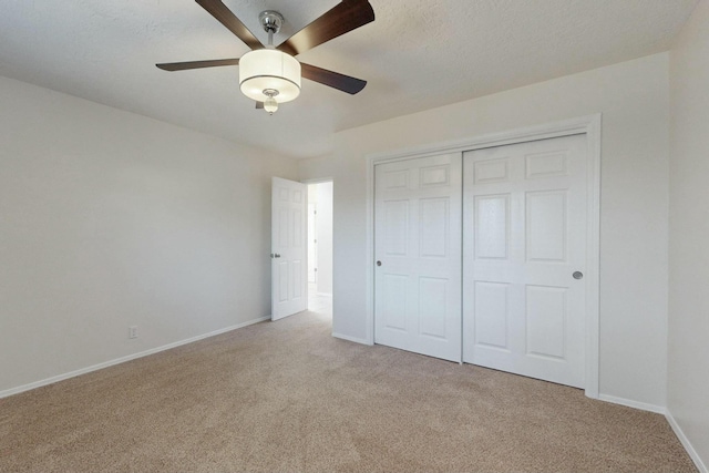 unfurnished bedroom featuring ceiling fan, light colored carpet, a closet, and a textured ceiling