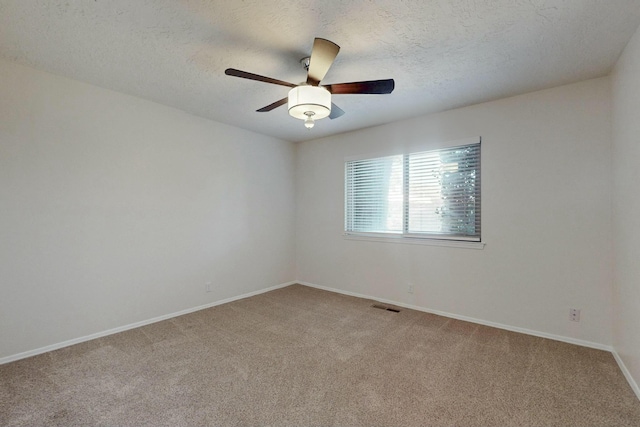 empty room with ceiling fan, light colored carpet, and a textured ceiling