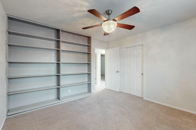 unfurnished bedroom featuring ceiling fan, light colored carpet, and a textured ceiling