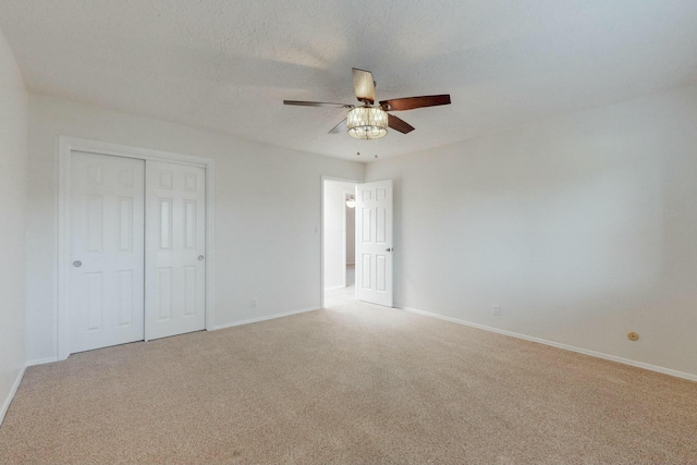 unfurnished bedroom with ceiling fan, light colored carpet, a textured ceiling, and a closet