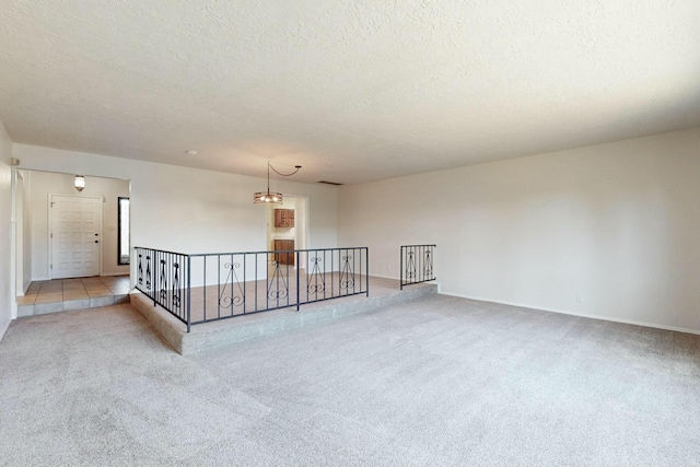 empty room with light colored carpet and a textured ceiling