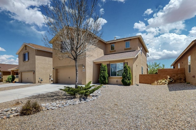 view of front of home with stucco siding, a garage, fence, and driveway