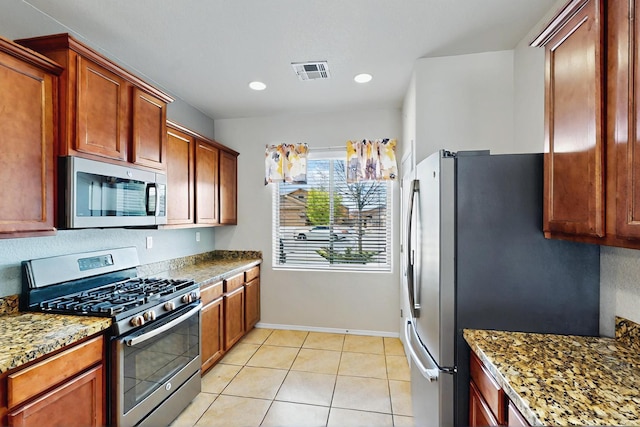 kitchen with baseboards, appliances with stainless steel finishes, stone counters, and visible vents