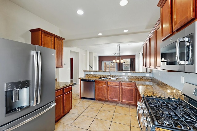 kitchen with a peninsula, light tile patterned flooring, light stone countertops, a sink, and stainless steel appliances