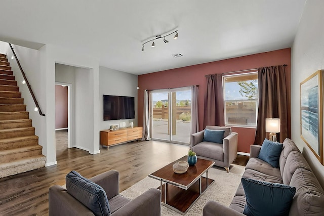living room with visible vents, track lighting, stairs, wood finished floors, and baseboards