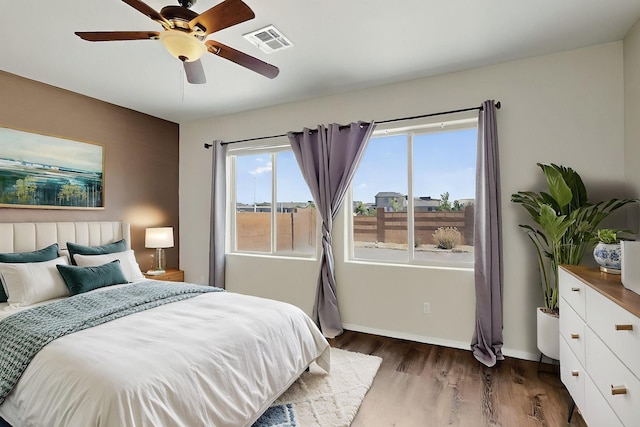 bedroom with baseboards, multiple windows, dark wood-style floors, and visible vents