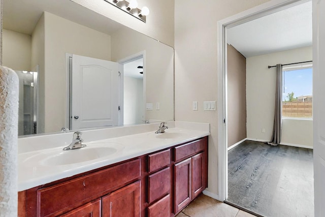 full bathroom featuring double vanity, baseboards, a sink, and wood finished floors