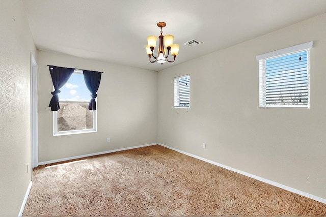 spare room with carpet floors, a chandelier, baseboards, and visible vents