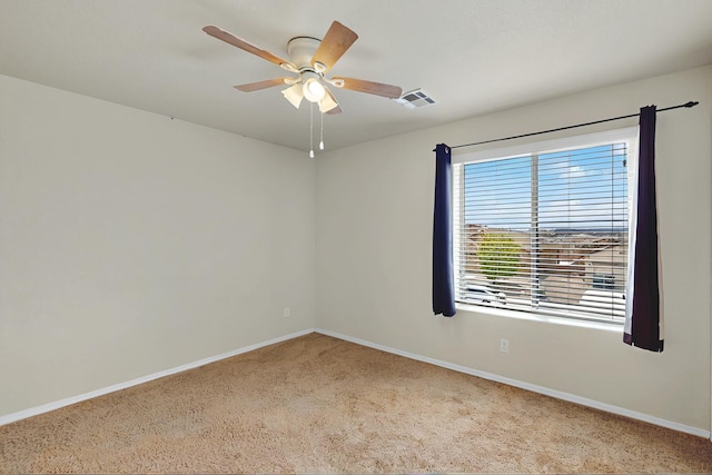 carpeted empty room with baseboards, visible vents, and ceiling fan