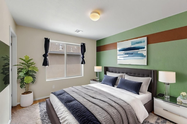 bedroom with baseboards, visible vents, and wood finished floors