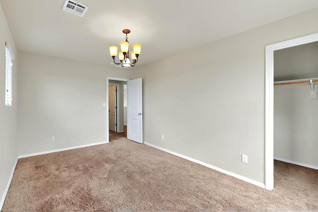 unfurnished bedroom featuring baseboards, visible vents, carpet flooring, and a notable chandelier