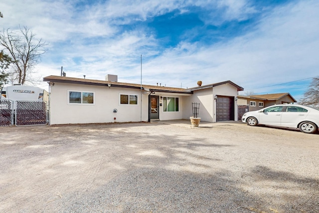 view of front of house with driveway, fence, an attached garage, and stucco siding