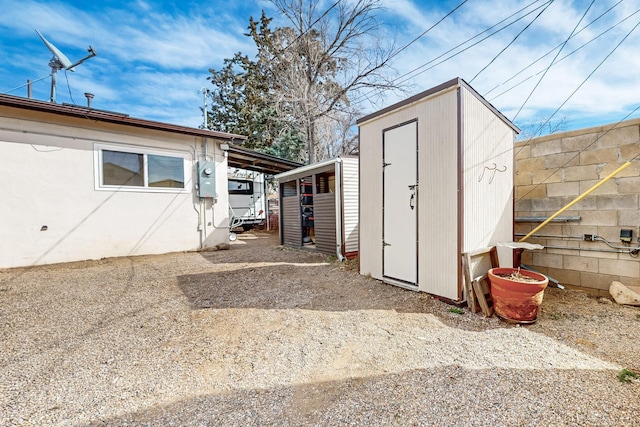 view of shed with driveway and an attached carport