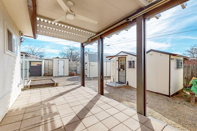 view of patio / terrace featuring a ceiling fan, an outbuilding, a fenced backyard, and a storage unit