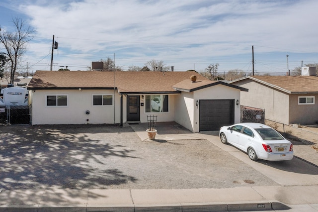 ranch-style house with concrete driveway, an attached garage, fence, and stucco siding