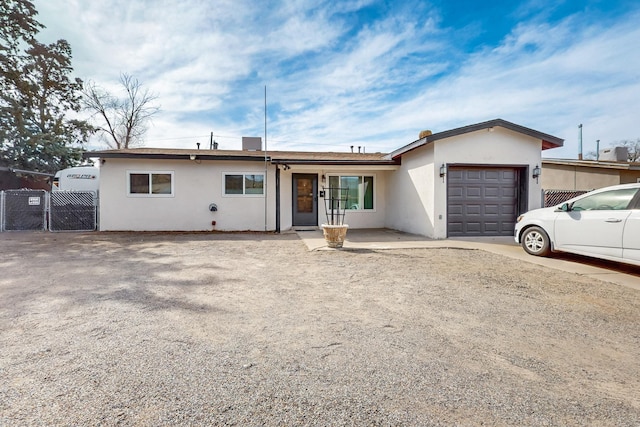 ranch-style home featuring a garage, driveway, fence, and stucco siding