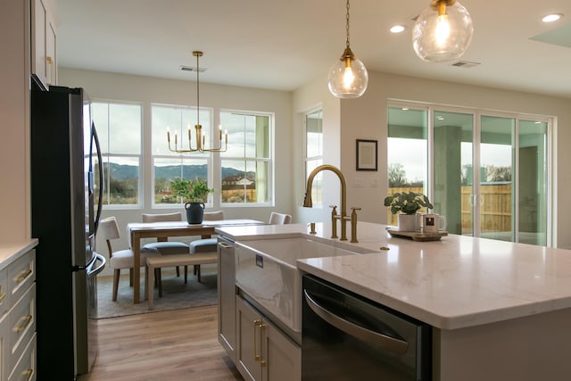 kitchen with freestanding refrigerator, dishwasher, plenty of natural light, light stone counters, and recessed lighting